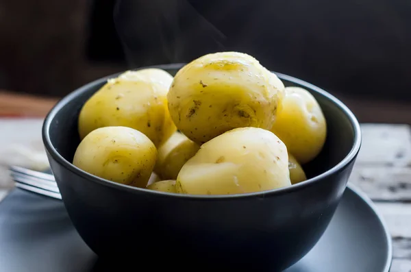 Sabrosas papas hervidas en tazón negro —  Fotos de Stock