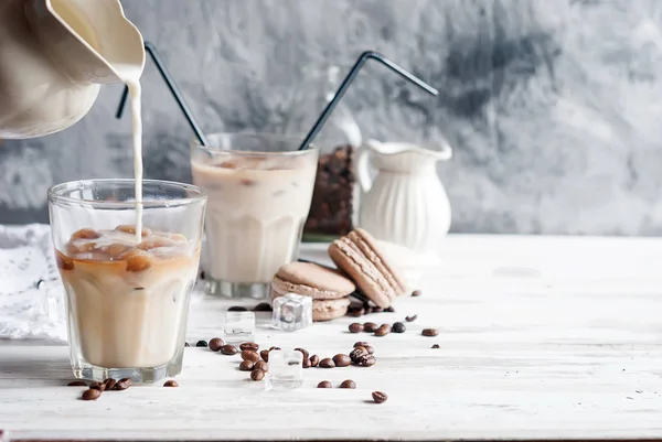 Процесс наливания молока в стакан со льдом кофе на сером фоне — стоковое фото