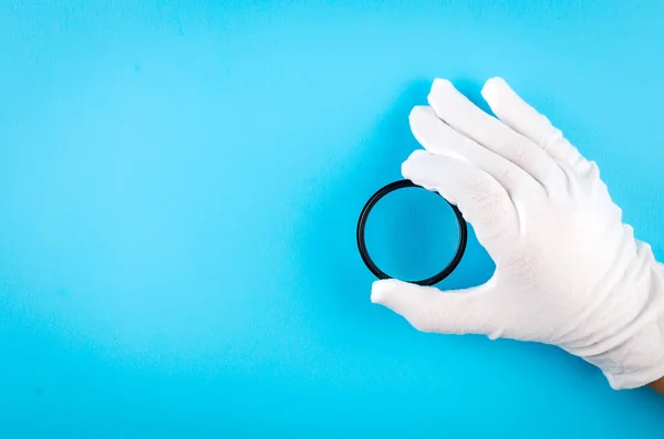 Рука в белой перчатке с объективом камеры — стоковое фото