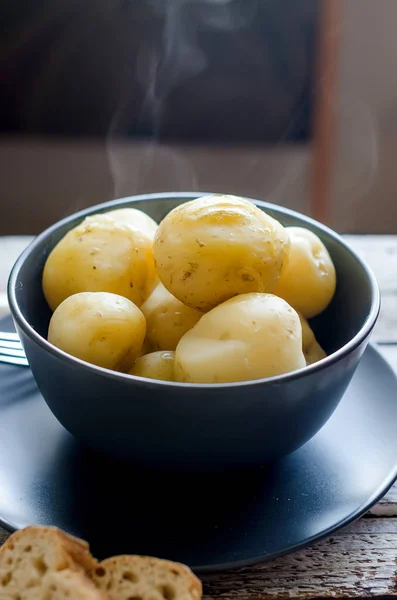 Tasty boiled potatoes in black bowl — Stock Photo, Image
