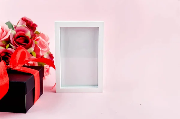 gift box, roses and empty frame on a pink background