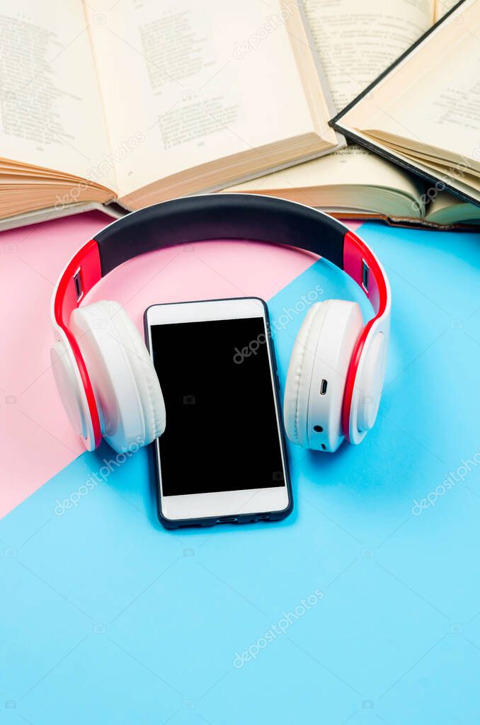 phone with earphones and open books on colored paper background. Audio book concept. modern education, reading. Listening to audiobooks, podcasts, and online courses. 