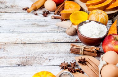 Sonbahar pişirme konsepti. Balkabağı, elma, fındık, sinamon, yumurta ve unla çerçevelenmiş ahşap masa. Malzemelerle pişirme işlemi. Üst Manzara. Boşluğu kopyala,