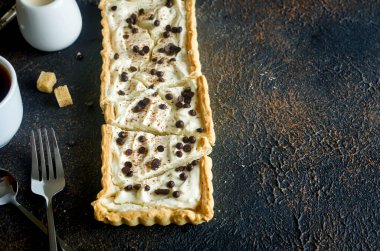 Vanilyalı tart ya da çikolata damlalı cheesecake ve koyu eski ahşap masada bir fincan kahve, fotokopi alanı, üst görünüm.