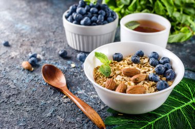 Kahvaltıda yaban mersinli tahıl gevreği ve bir fincan çay, fındıklı ev yapımı müsli ve az tatlı olsun diye bal..