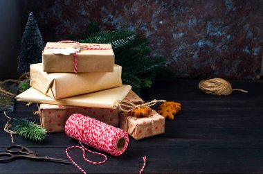 Noel kompozisyonu. İçinde bir sürü el işi hediye kutusu, köknar brandı ve siyah ahşap masa üzerinde zencefilli ekmek var. Tatil konsepti arkaplan, üst görünüm, kopyalama aralığı