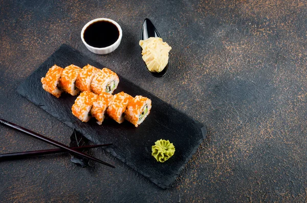 美味的加利福尼亚卷和Maki放在石盘上 生姜和芥末放在黑暗的桌子上 亚洲菜单 日本食品递送服务 杂烩寿司 — 图库照片