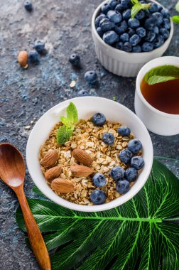 Kahvaltıda yaban mersinli tahıl gevreği ve bir fincan çay, fındıklı ev yapımı müsli ve az tatlı olsun diye bal..