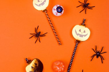 Cadılar Bayramı partisi kompozisyonu turuncu kağıt arka planda. Düz yatış, Cadılar Bayramı partisi dekorasyonu - pipet, balkabağı, yarasa ve örümcekler için. Model, tebrik kartı, düz yatak, üst görünüm.