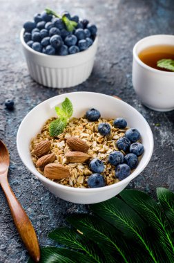 Kahvaltıda yaban mersinli tahıl gevreği ve bir fincan çay, fındıklı ev yapımı müsli ve az tatlı olsun diye bal..