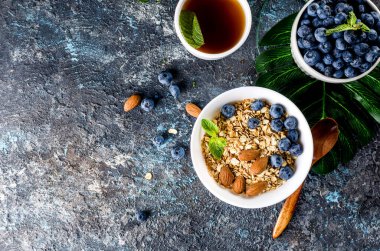 Kahvaltıda yaban mersinli tahıl gevreği ve bir fincan çay, fındıklı ev yapımı müsli ve az tatlı olsun diye bal..