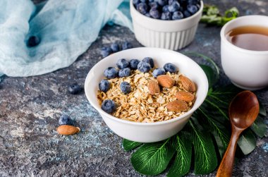 Kahvaltıda yaban mersinli tahıl gevreği ve bir fincan çay, fındıklı ev yapımı müsli ve az tatlı olsun diye bal..