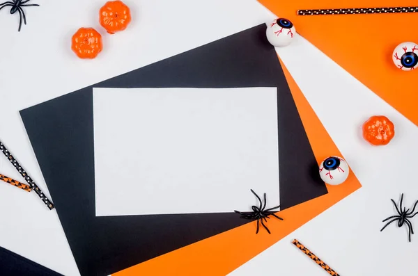 Halloween party composition on paper background in black, orange and white. Flat lay, Halloween party decor - drink straws,  pumpkins, bats and spiders. Mock-up, greeting card, flat lay, top view.