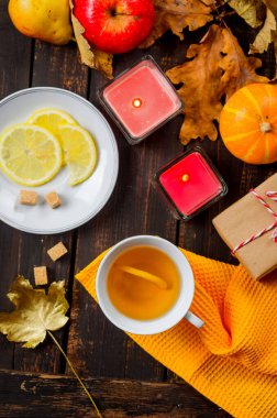 Sonbahar, bir fincan çay, balkabağı ve ahşap arka planda yapraklarla sakin bir hayattır.