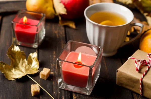 Composición de otoño con velas, calabazas y hojas de otoño, taza de té en la mesa de madera. — Foto de Stock