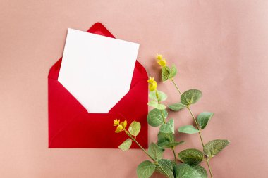 Mesaj için boş beyaz kart ve bej arka planda kırmızı zarf. Davetiye ya da tebrik kartı modeli. İleti için en küçük kavram, 