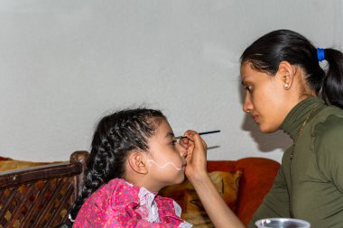 Anne, festival için kızının yüzüne Catrina makyajı yapıyor.