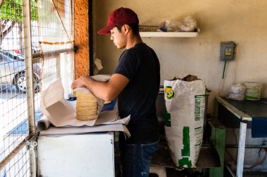 Genç adam tipik bir Meksika dükkanında nixtamal tortilla satıyor.