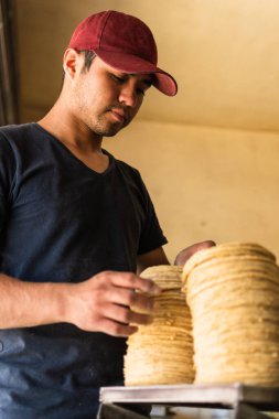 Genç adam tipik bir Meksika dükkanında nixtamal tortilla satıyor.