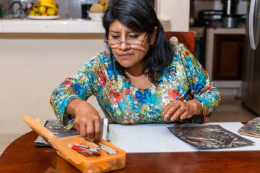 Kadın kendi elleriyle metal kabartmalı çerçeve yapıyor.