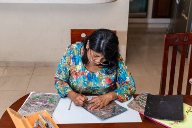 Kadın kendi elleriyle metal kabartmalı çerçeve yapıyor.