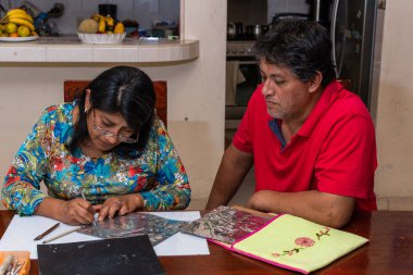 Kadın ve erkek kendi elleriyle metal kabartmalı çerçeve yapıyorlar.