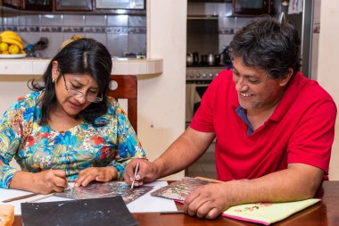 Kadın ve erkek kendi elleriyle metal kabartmalı çerçeve yapıyorlar.