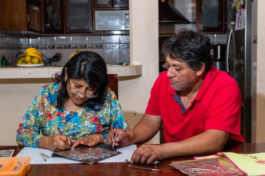 Kadın ve erkek kendi elleriyle metal kabartmalı çerçeve yapıyorlar.