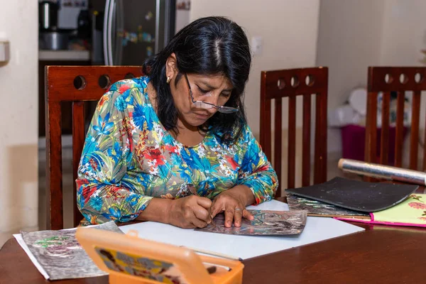 Kadın kendi elleriyle metal kabartmalı çerçeve yapıyor.