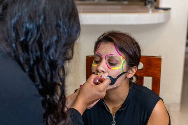 Kadın başka bir kadına makyaj yapıyor. Ölüler günü partisi için.