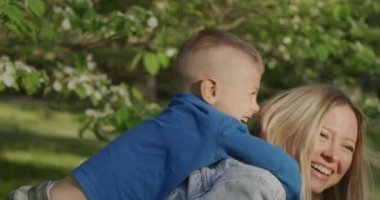 Güzel genç bir kadın oğluyla eğleniyor. Annesinin sırtında küçük bir çocuk