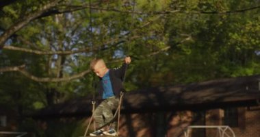 Yeşil bir parkta salıncakta sallanan küçük bir çocuk. Mutlu çocukluk.