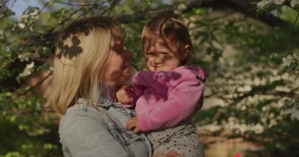 Mooie vrouw houdt haar baby meisje op haar armen in de zomer park — Stockvideo