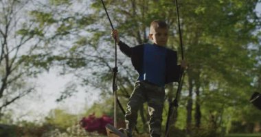 Yeşil bir parkta salıncakta sallanan küçük bir çocuk. Mutlu çocukluk.
