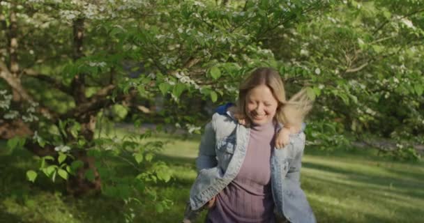 Uma jovem bonita a divertir-se com o seu menino. Menino nas costas da mãe — Vídeo de Stock