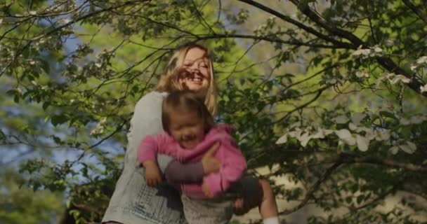 Mulher bonita segura sua menina em seus braços no parque de verão — Vídeo de Stock