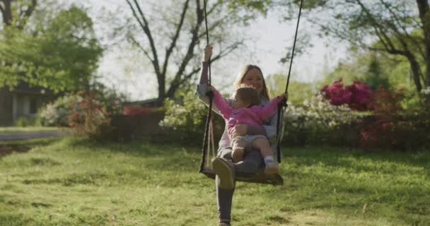 Młoda kobieta z córeczką na huśtawce. ładna młoda mama z jej dziewczynka w parku — Wideo stockowe