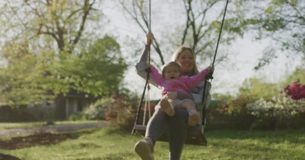 Młoda kobieta z córeczką na huśtawce. ładna młoda mama z jej dziewczynka w parku — Wideo stockowe