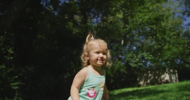 Nettes kleines Mädchen springt im Sommerpark. Rote Kinokamera. Zeitlupe 4k — Stockvideo