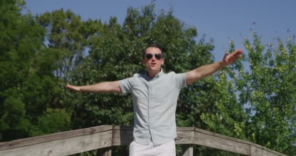 Młody ładny mężczyzna śpiewa i tańczy w letnim parku 4k — Wideo stockowe