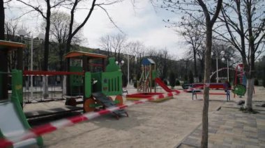 Açık havada renkli oyun parkları kapalı. Çocuklar için oyun merkezi, karantina ve COVID-19 uzatma önlemesi nedeniyle kırmızı beyaz şeritli barikatla kapatıldı. Çocukluğun sonu..