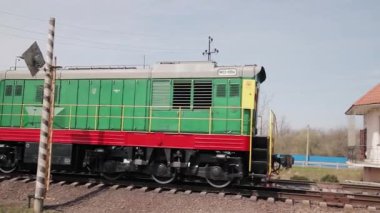 İzmail, Ukrayna - 2020 baharında. Editör kullanımı. Arabasız tren ön planda kırmızı ve beyaz şeritli bariyer ile demiryoluna çıkıyor..