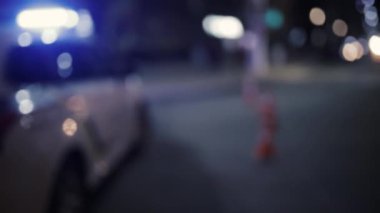 Şehir yolunda sirenleri ve trafik konileri olan polis arabasının odaklanmamış görüntüsü. Acil durum ya da suç mahalli. Gece ışıkları bokeh.