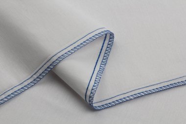 Sade dokumadan beyaz pamuk kumaş, mavi ipliklerle bağlanıyor ve bağlanıyor, örnek