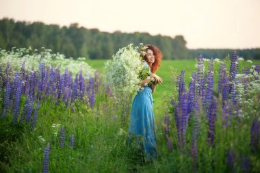 Bir yaz akşamında çiçek tarlasında büyük bir buketi olan genç bir kadın.