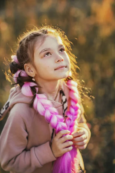 Bir yaz akşamı yürüyüş yapan pembe saçlı bir kız.