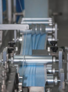 Spandbond 'tan yapılmış koruyucu maskelerin üretimi için otomatik hattın bir bölümü, malzeme üç katlı olarak yerleştirilmiştir.