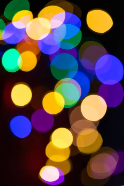 Christmas multicolored lights in defocus on a dark background