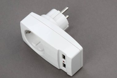 Gri kağıt arkaplanda iki USB konnektörü olan bir elektrik prizi için adaptör
