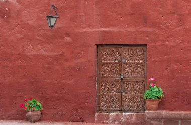Arequipa, Peru 'da çiçek saksıları, fener ve kırmızı duvarlı güzel antik kapı.